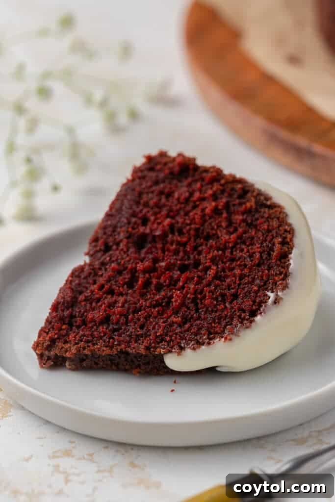 A perfectly sliced piece of moist red velvet bundt cake, showing its rich red color and soft texture.
