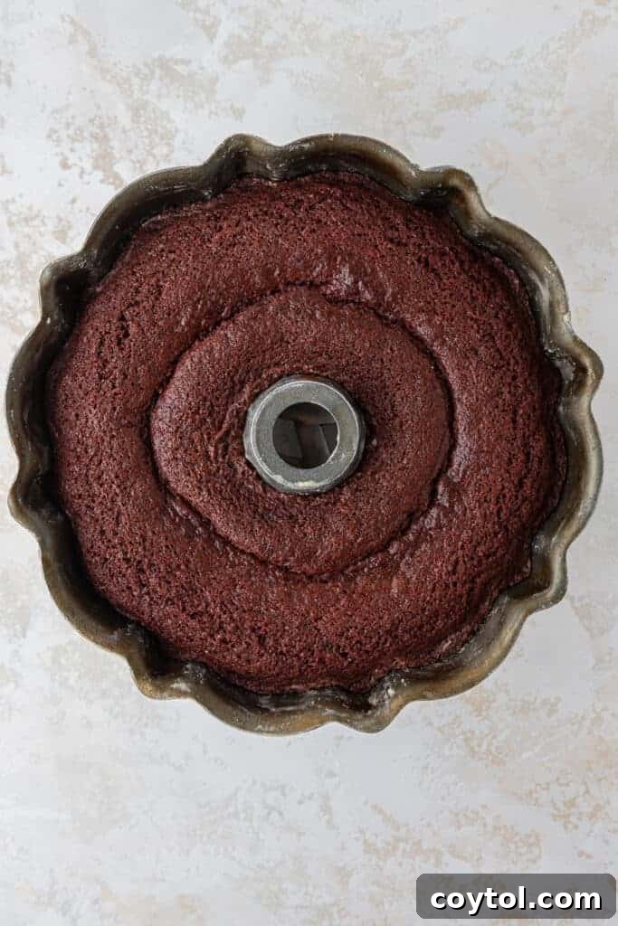 A perfectly baked red velvet bundt cake cooling on a wire rack, ready for glazing.