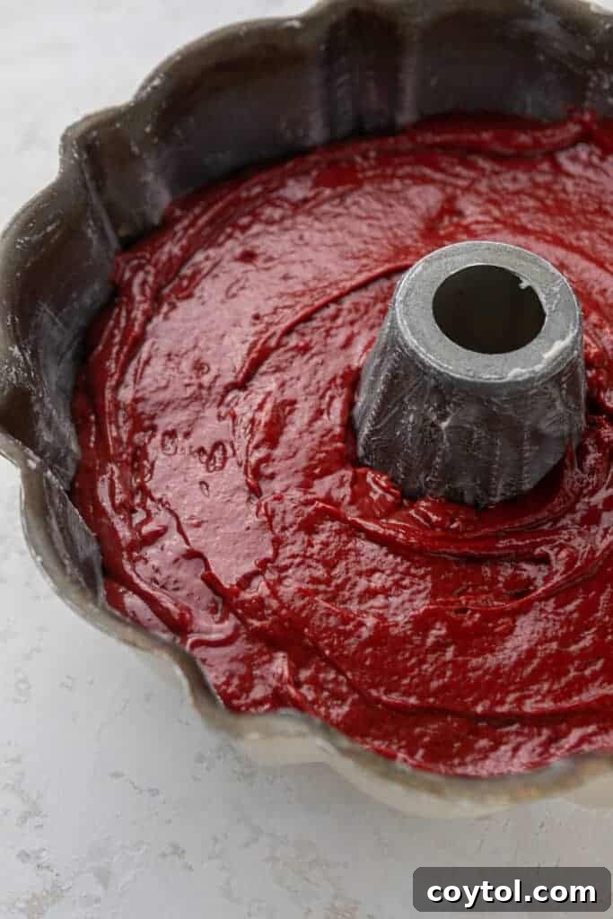 Red cake batter beautifully swirled into a bundt pan, ready for baking.
