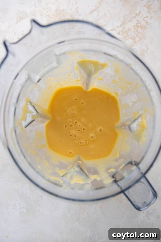 Creamy tropical smoothie being blended in a high-speed blender, showing its smooth texture.