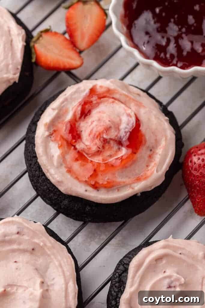 Chilled Strawberry Cheesecake Swirl Chocolate Cookies 13 An Oreo strawberry cheesecake cookie, showing the dark cookie base, pink frosting, and a strawberry.