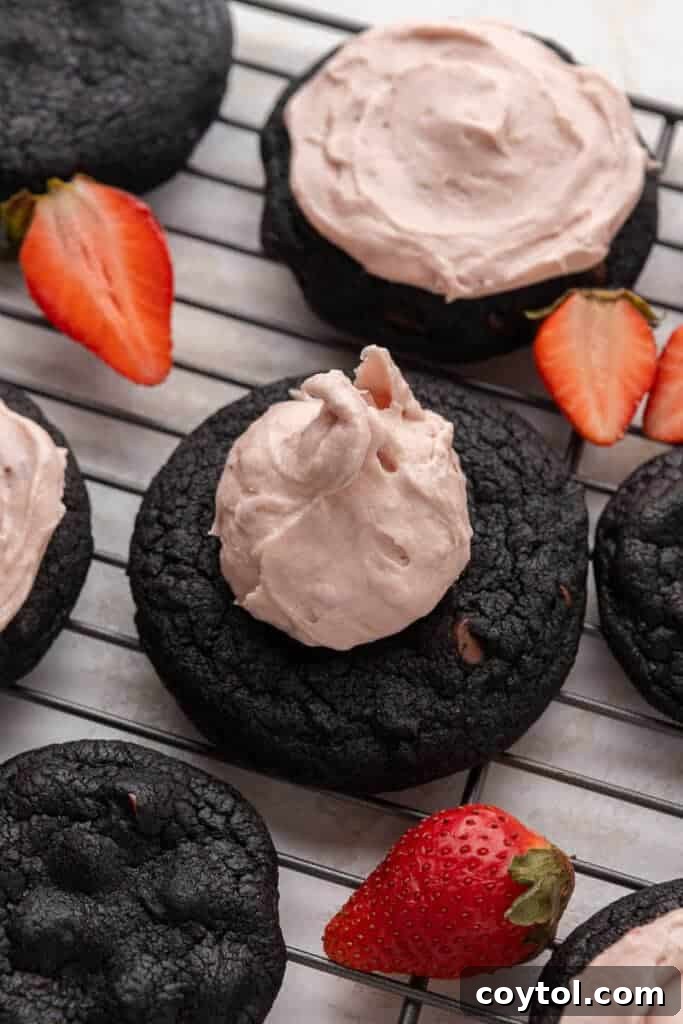 Chilled Strawberry Cheesecake Swirl Chocolate Cookies 9 Chocolate strawberry cheesecake cookie with a thick layer of pink frosting, topped with fresh strawberry slices.
