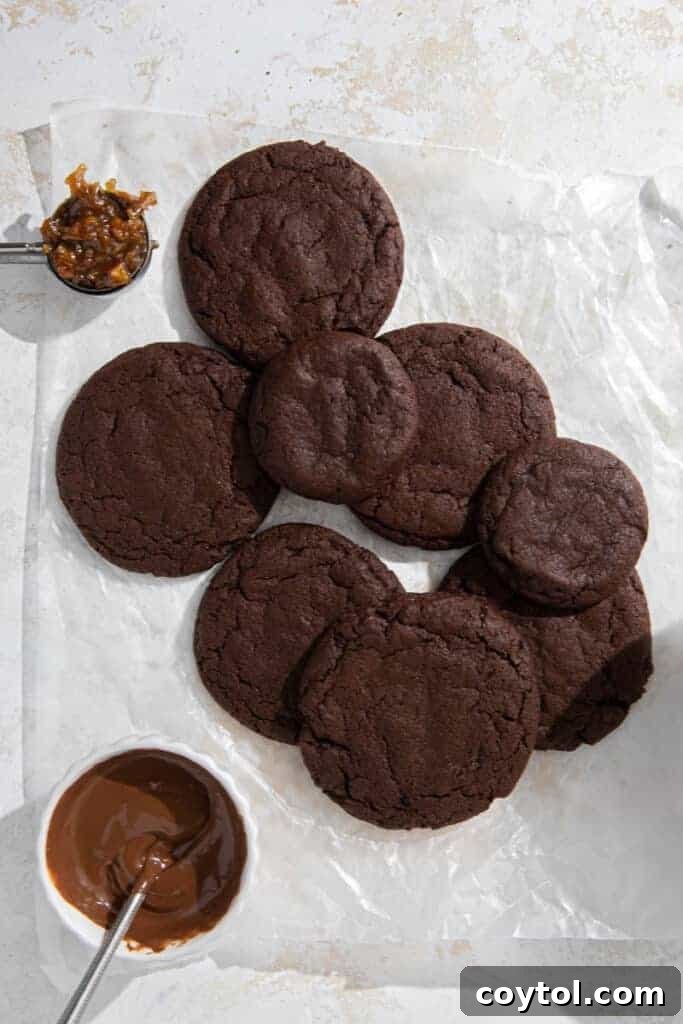 Warm, freshly baked chocolate cookies cooling on a baking sheet, showing their slightly puffed appearance.