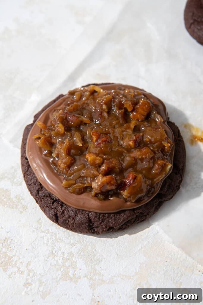 A tray of beautifully frosted Crumbl German Chocolate Cake Cookies, complete with chocolate drizzle and pecan coconut topping.