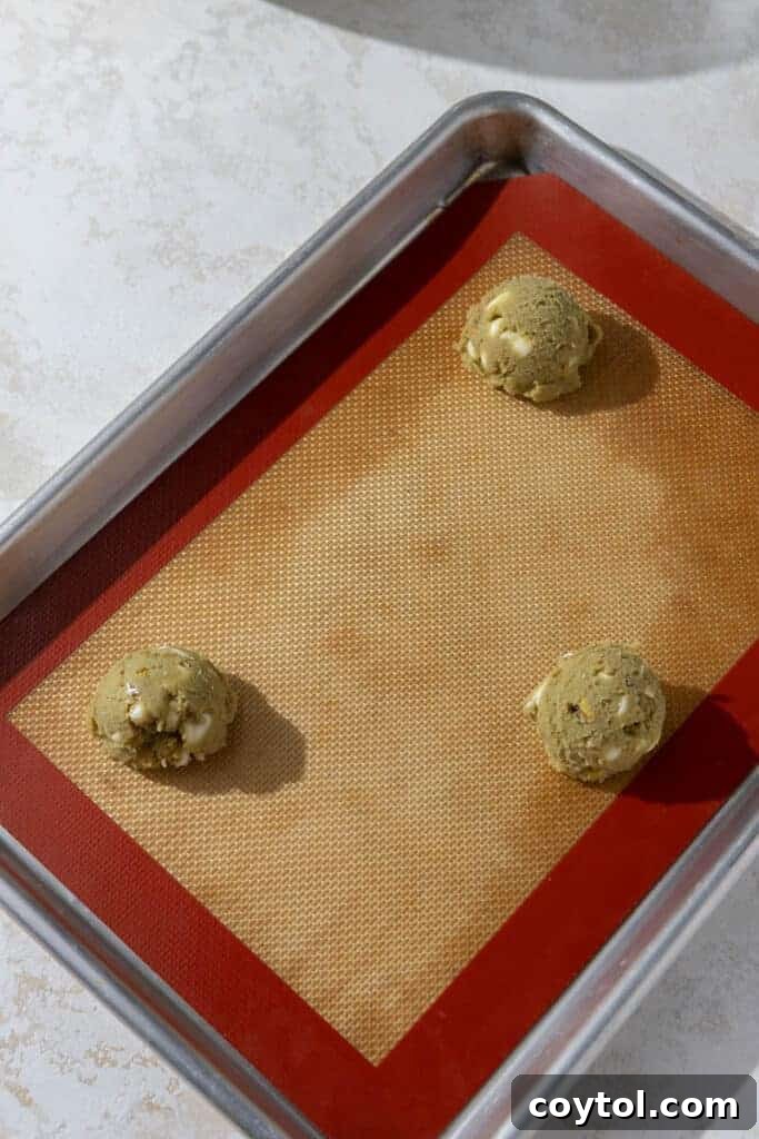 Cookie dough balls arranged on a baking sheet lined with parchment paper.