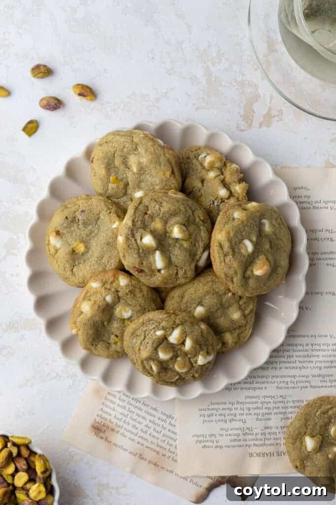 Freshly baked pistachio cookies cooling on a plate.