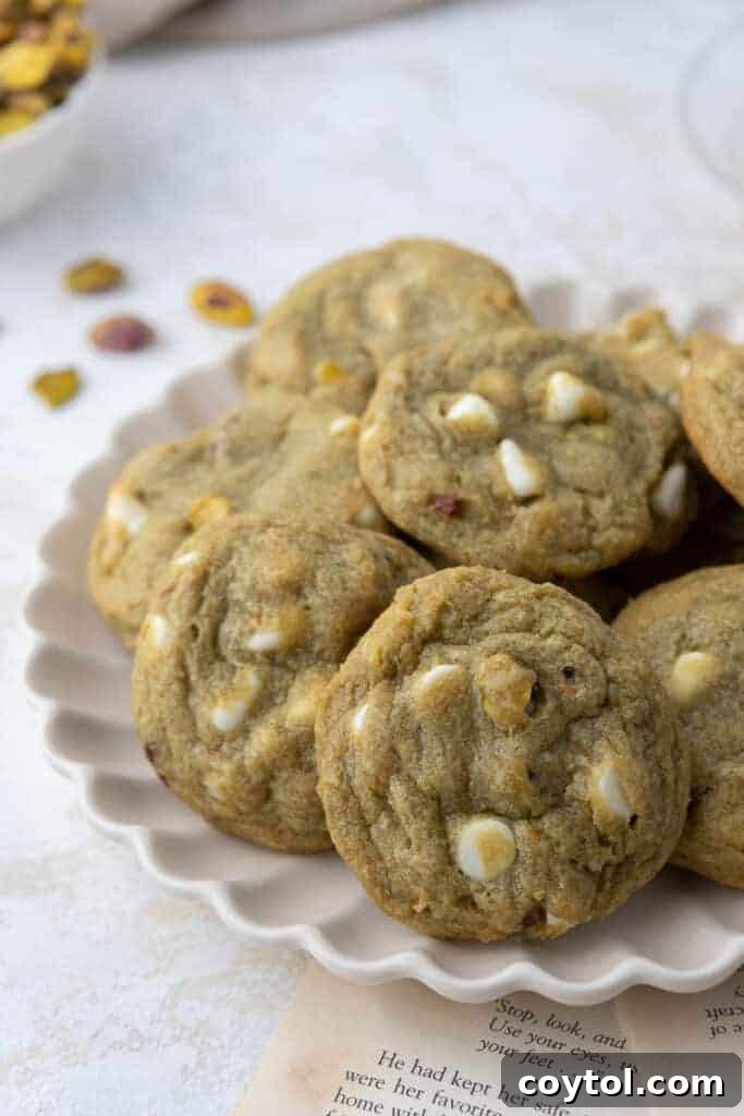 Stack of Pistachio Pudding Cookies with white chocolate chips on a wooden surface.
