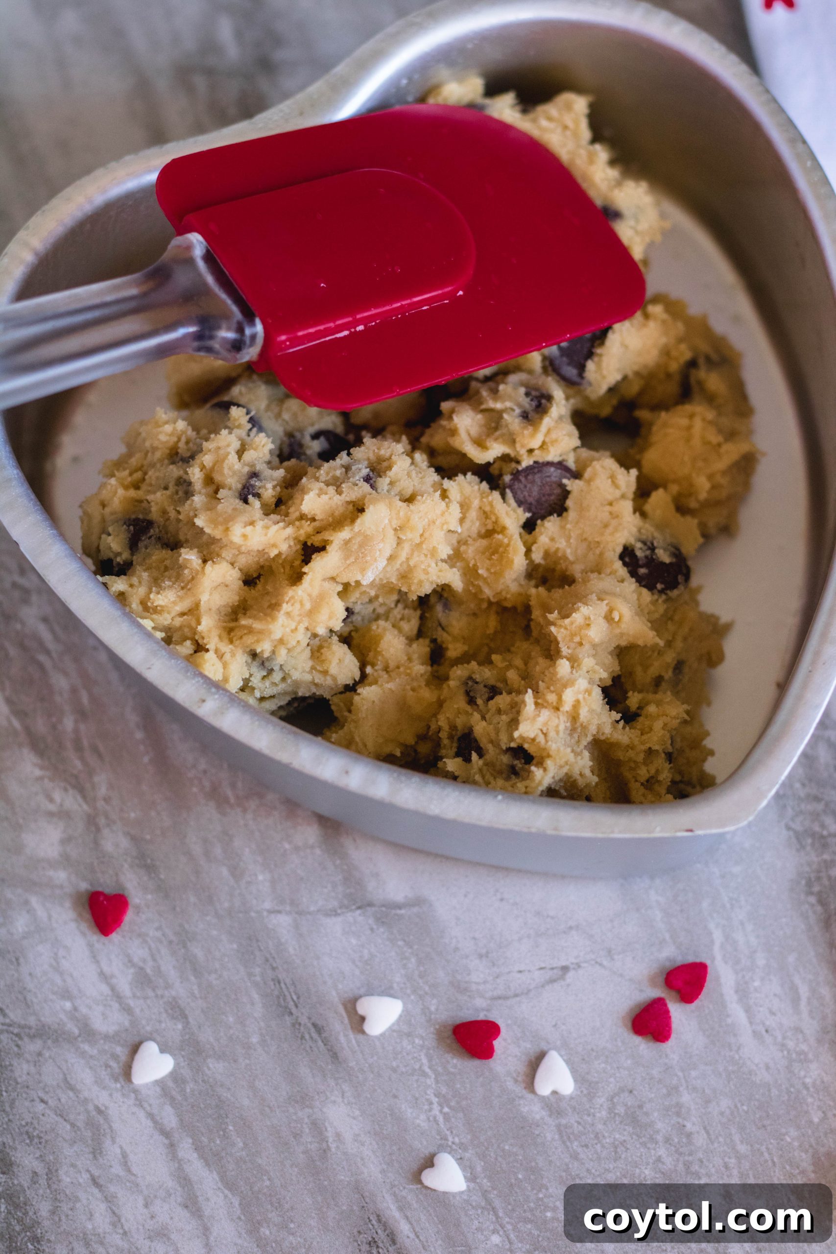 Spreading chocolate chip cookie dough evenly in a heart baking pan