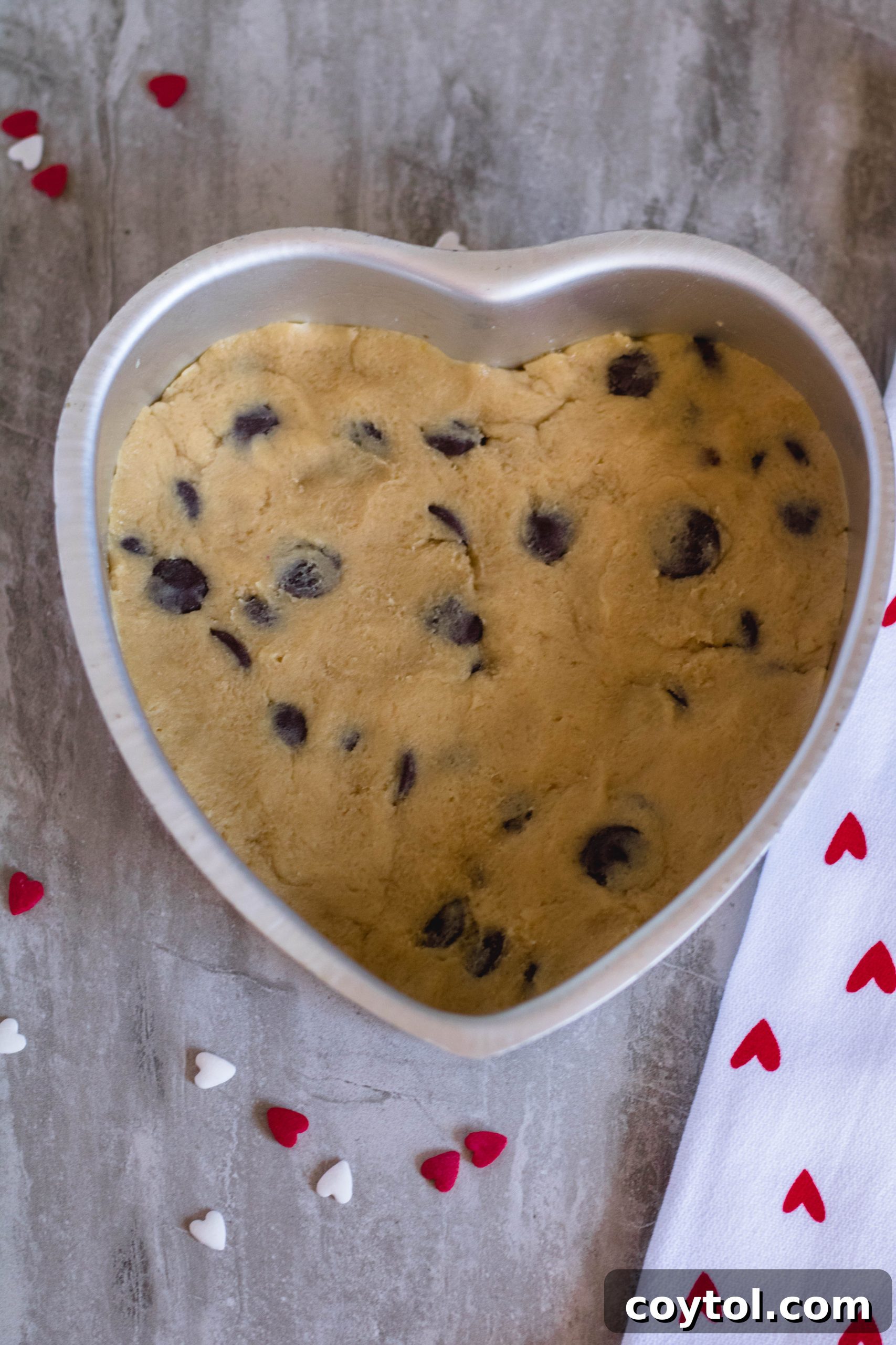 Heart-shaped cookie dough pressed into a baking pan, ready for chilling