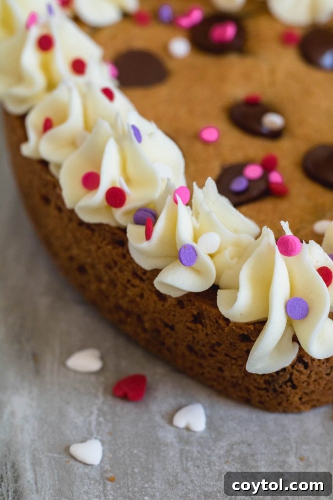 Decorated heart cookie cake with piped white chocolate ganache and sprinkles