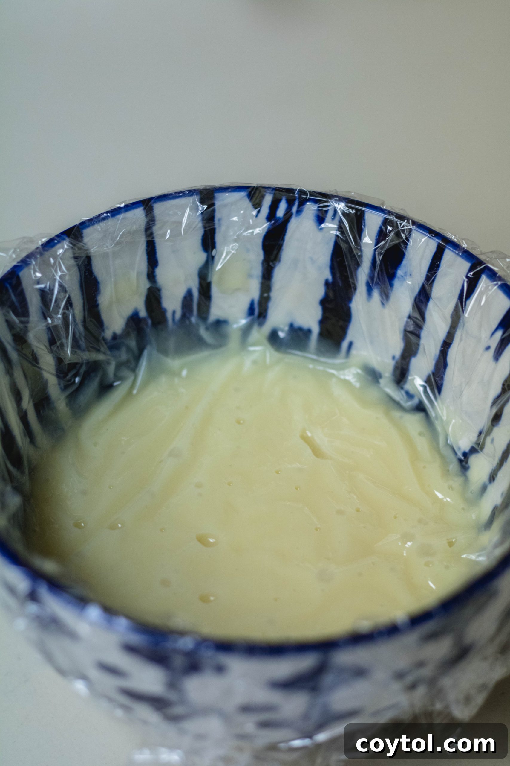 White chocolate ganache cooling with plastic wrap directly on the surface