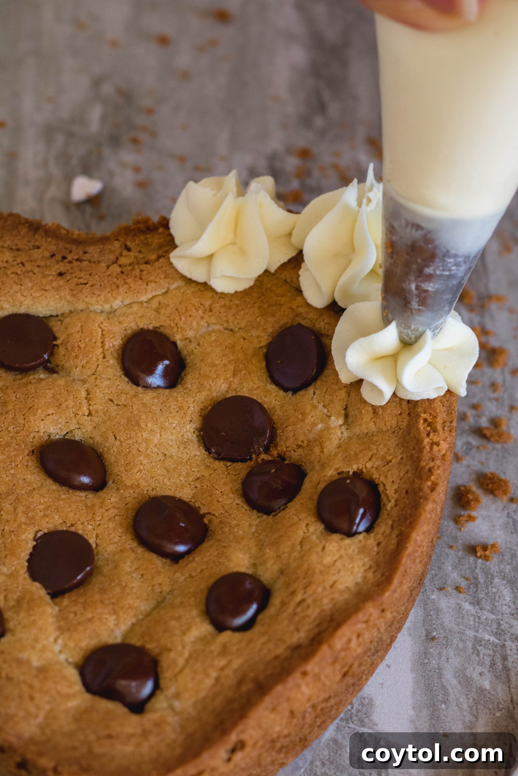 Piping the white chocolate ganache around the edge of the heart cookie cake