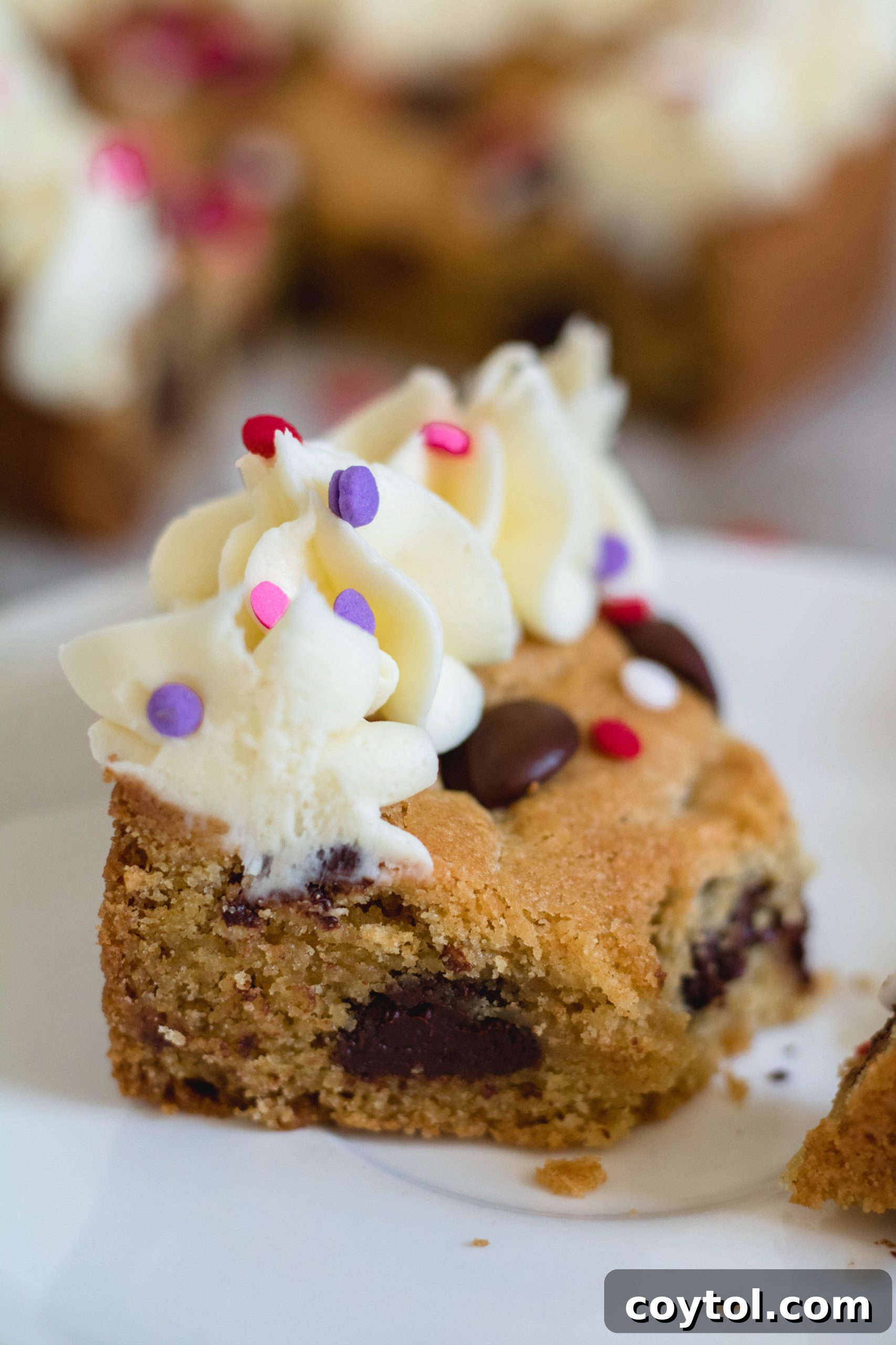 Heart-shaped Valentine's Day cookie with white chocolate ganache and sprinkles on a white plate