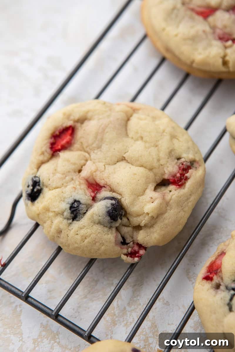 Baked Berries and Cream cookie resting on a cooling rack, showing its golden edges and soft texture.