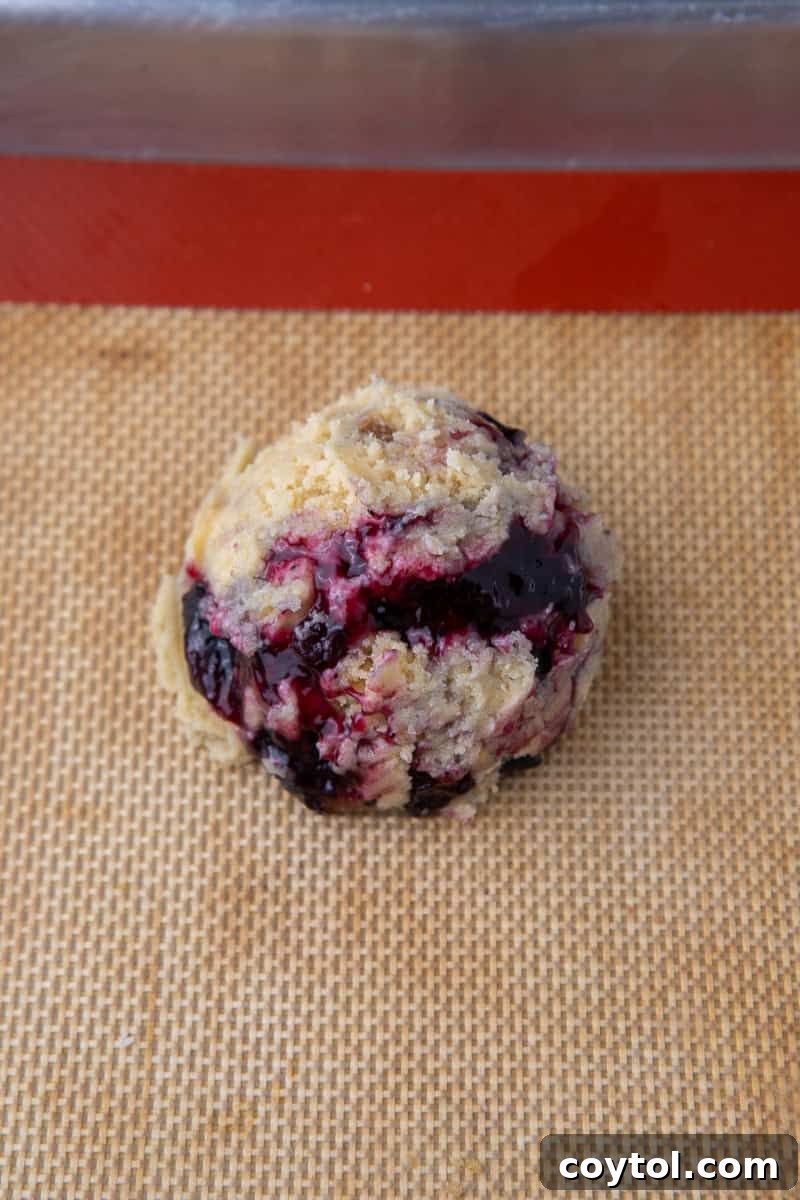 Blueberry Muffin Cookie Bliss: Crumbl-Style with Streusel 8 Portioned blueberry muffin cookie dough on baking sheet