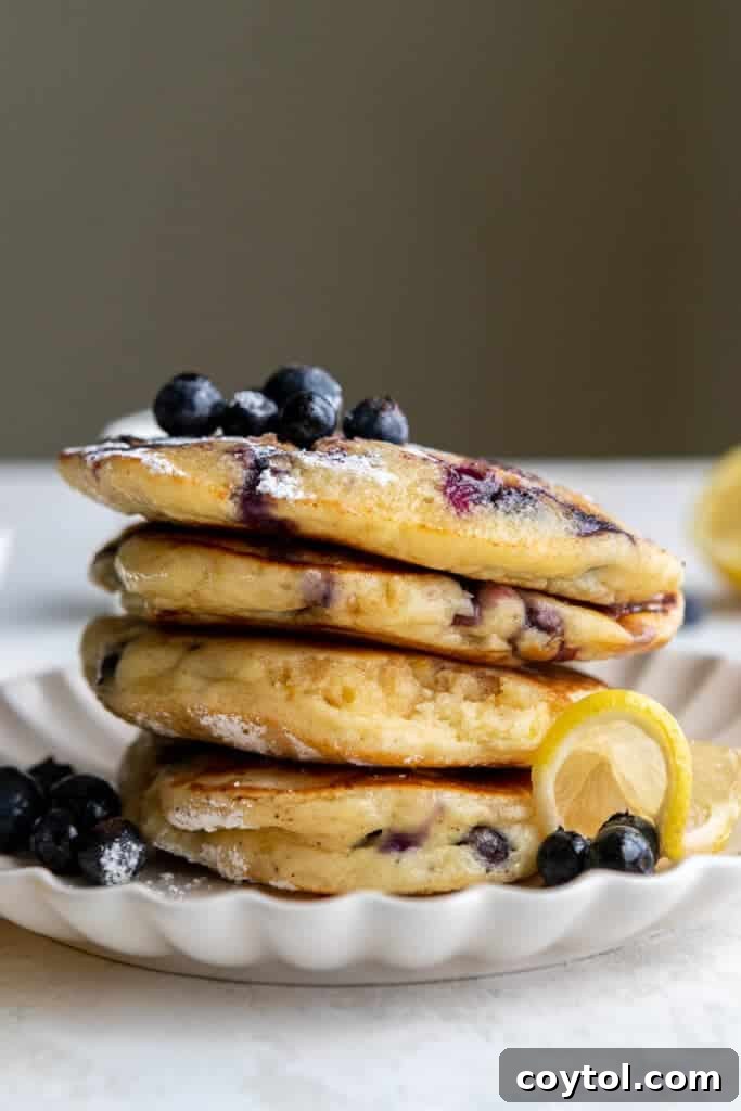 Stacked lemon ricotta pancakes with blueberries and lemon slices