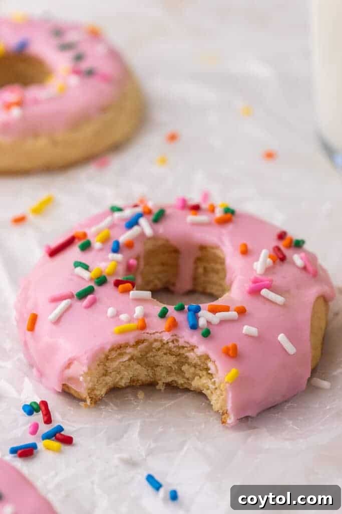 A Crumbl pink donut cookie with a bite taken out, showing the soft interior