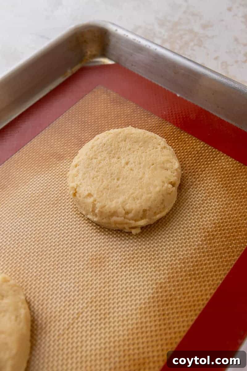 Scooped sugar cookie dough balls flattened on a baking sheet