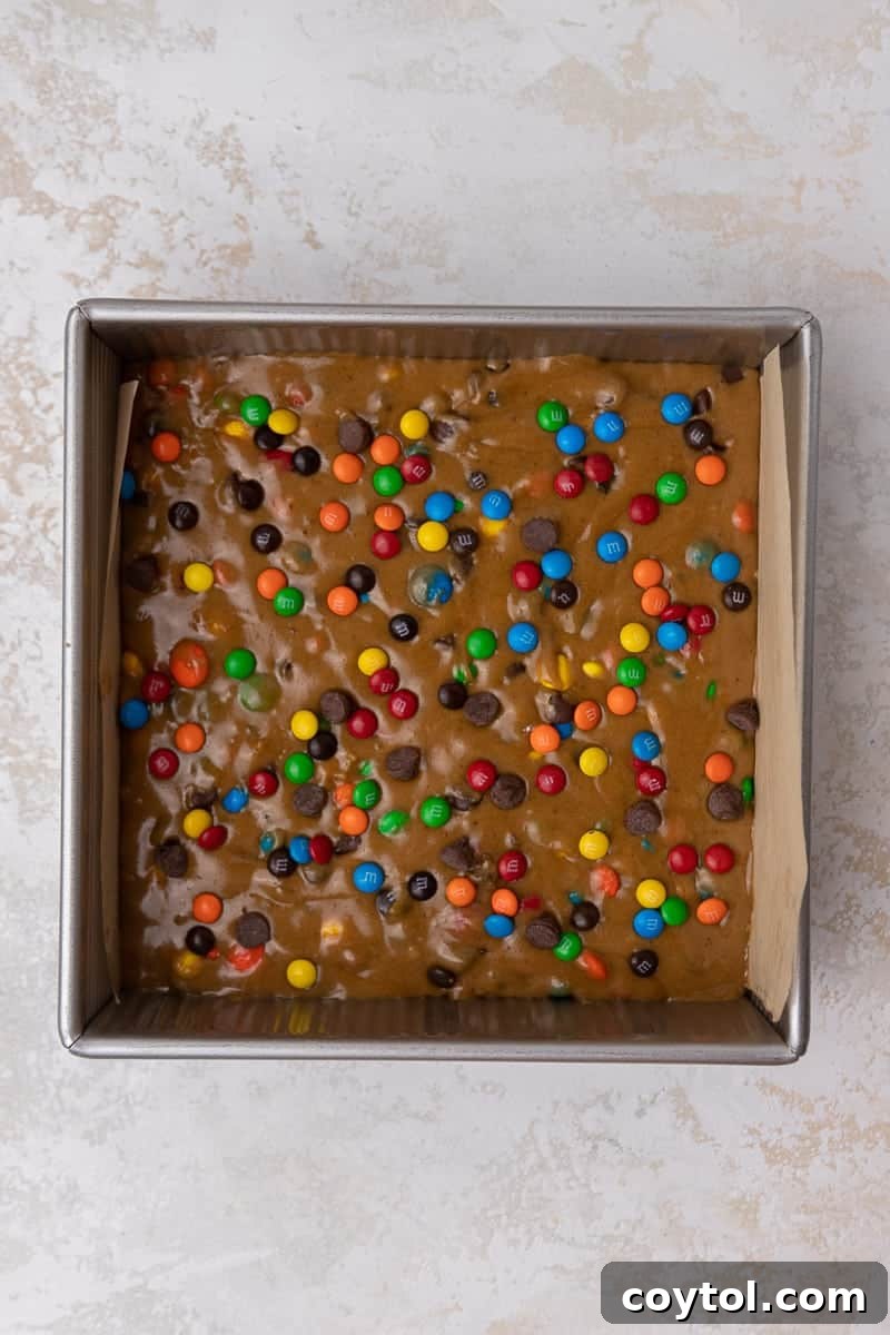 Chewy M&M Chocolate Chip Blondie Bars 7 M&M's blondie dough spread evenly into an 8x8 inch baking pan, ready for the oven