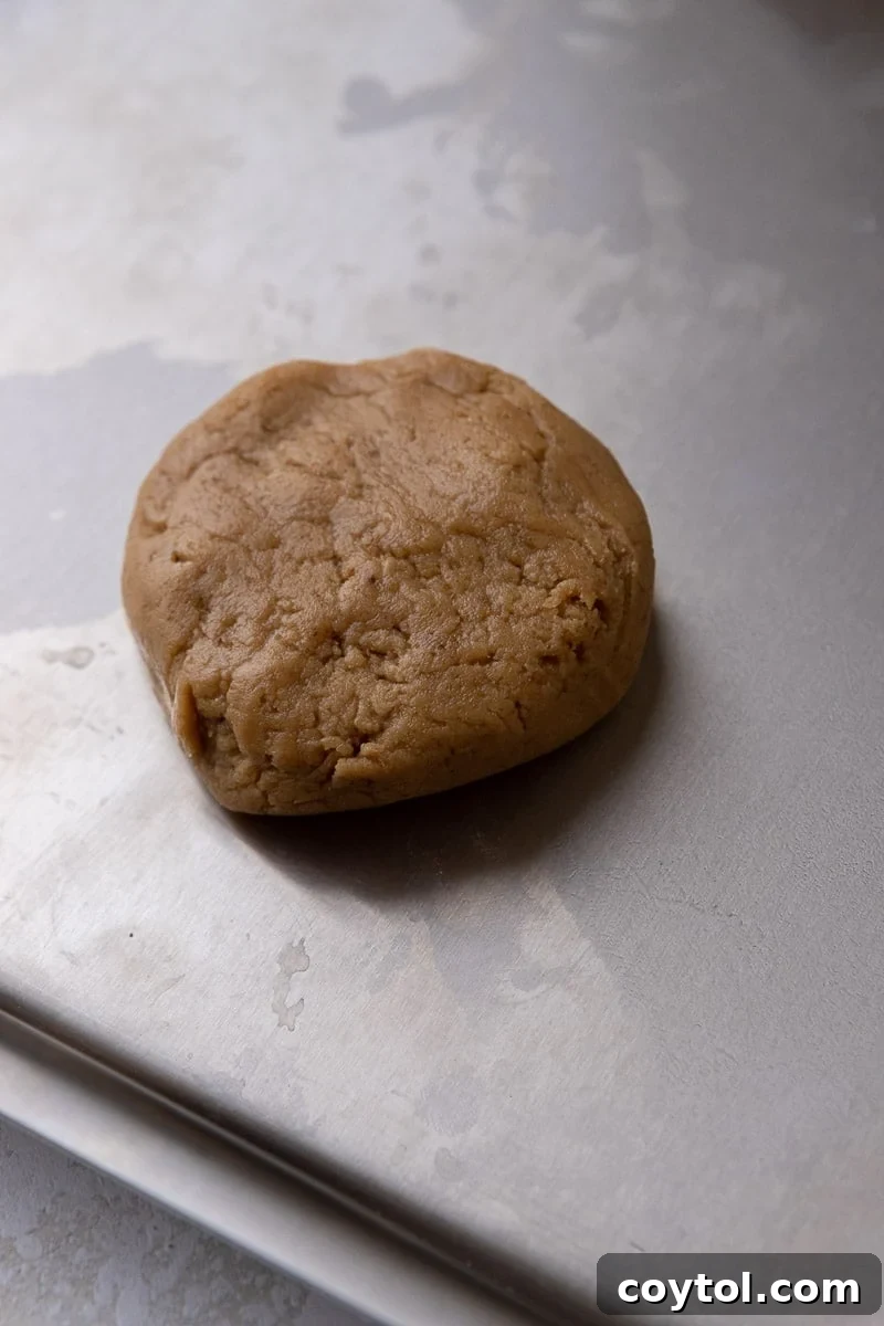 Crumbl's Chilled Cookie Butter Ice Cream Cookies 7 Brown sugar cookie dough balls on a baking sheet, gently flattened.