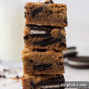 Stack of golden brown fudgy Oreo blondies with visible cookie chunks and a rich, nutty brown butter base.