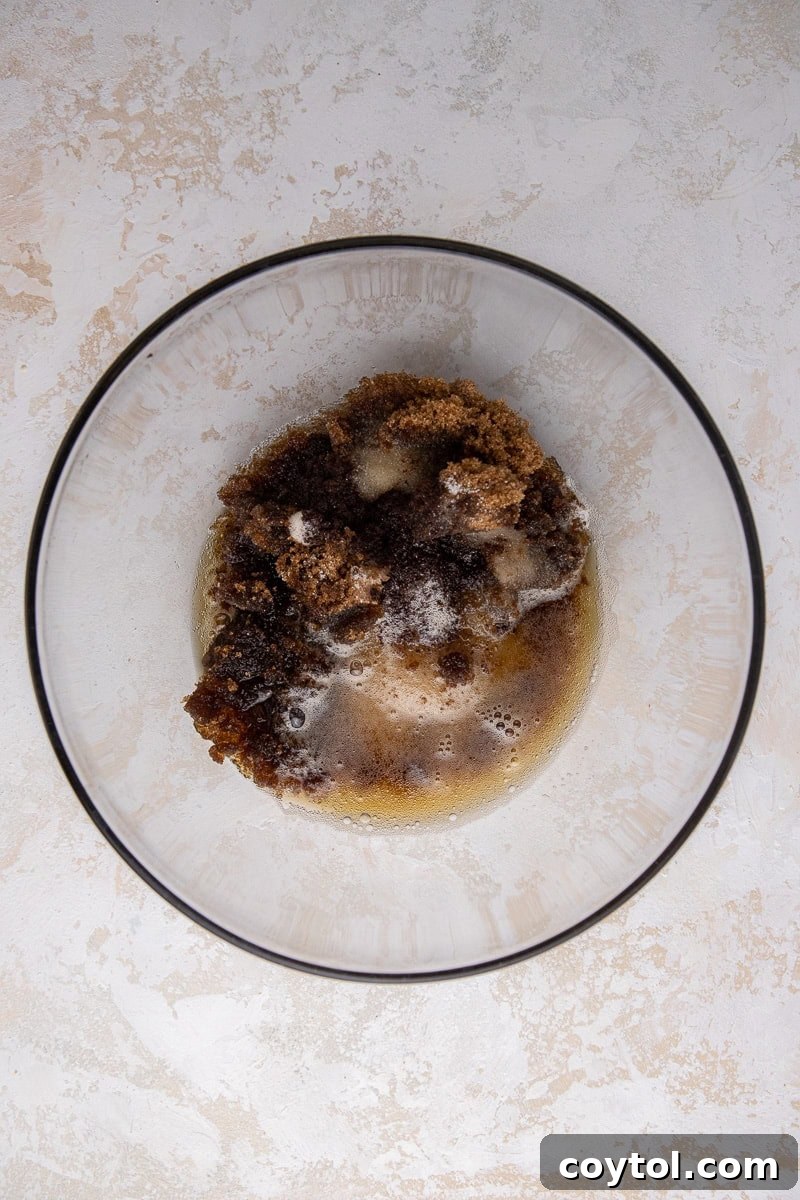 Melted brown butter with a foamy top and golden-brown flecks in a glass bowl, illustrating the first step of the recipe.
