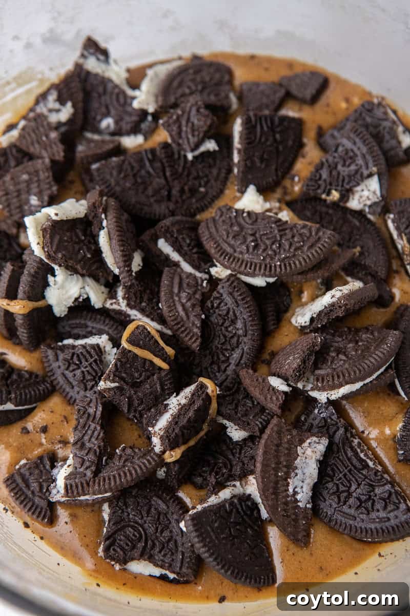 Thick blondie batter with generously folded in roughly chopped Oreo cookie pieces, ready for baking.