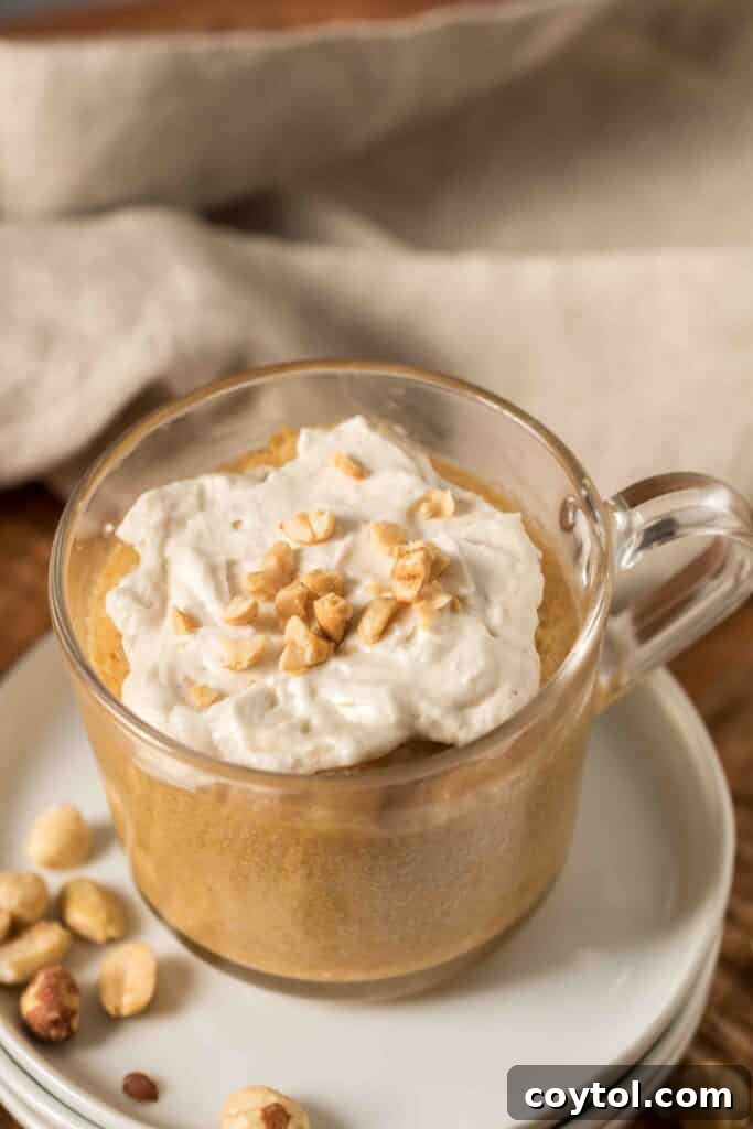 A delicious, moist peanut butter mug cake topped with a dollop of cream