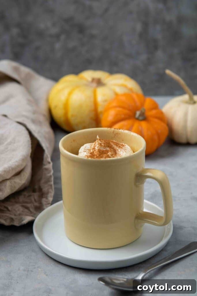 Close up of a vibrant pumpkin mug cake in a yellow mug, topped with vanilla frosting