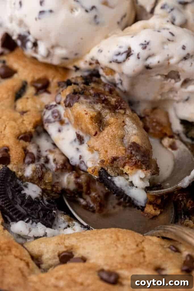 Simple Skillet Oreo Cookies and Cream Pizookie 2 Close-up view of a warm, freshly baked cookies and cream skillet cookie topped with melted ice cream and Oreo crumbles.