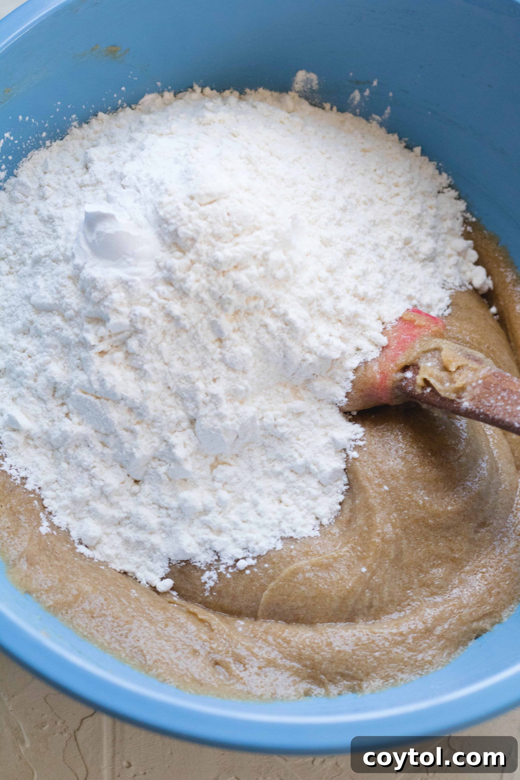 Adding dry ingredients to the wet blondie mixture, a crucial step for achieving the right texture.