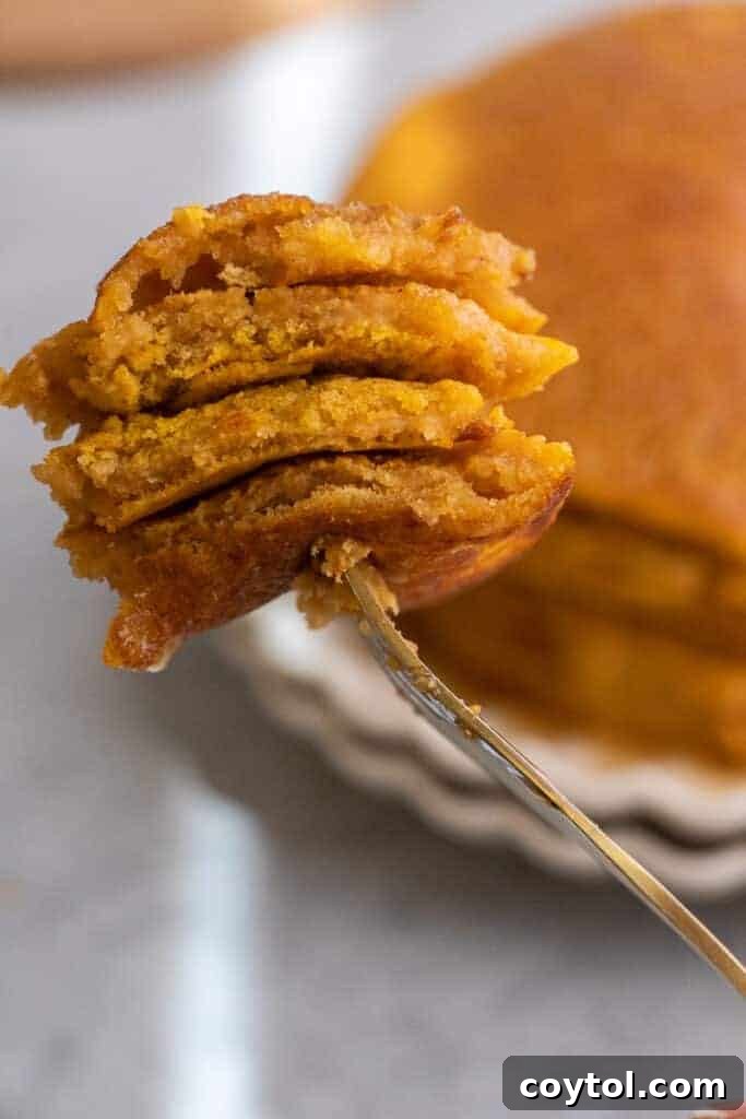 Fluffy pumpkin pancakes made with pancake mix, drizzled with syrup and topped with whipped cream, garnished with fall leaves.