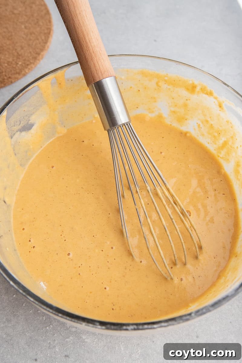 Whisked pumpkin pancake batter with a few small lumps, ready for cooking.