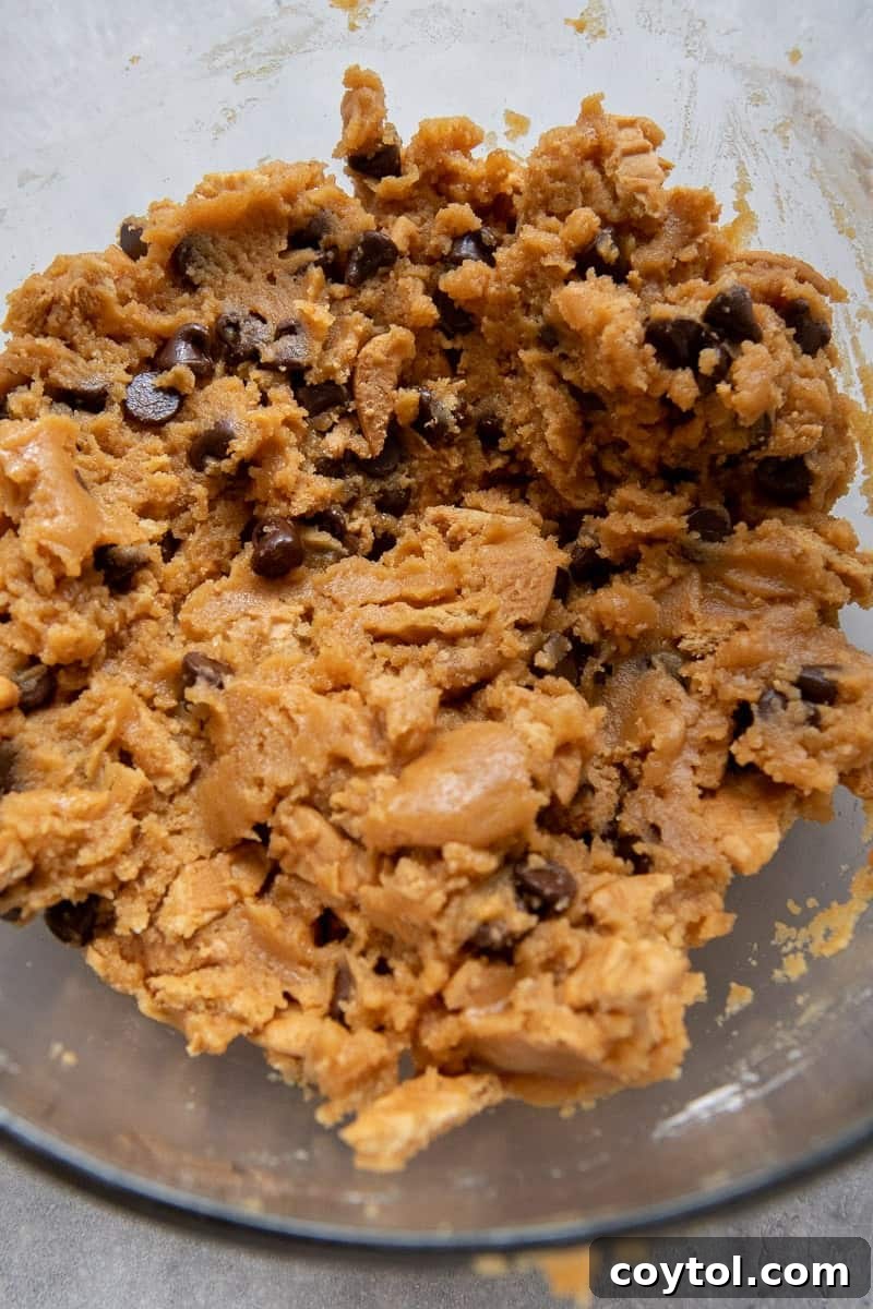 Close-up of the rich, thick cookie dough in a mixing bowl, showing the texture and ingredients.
