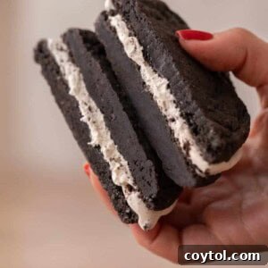 Crumbl's Mallow Oreo Dream Sandwich 13 Hand holding Crumbl mallow oreo cookie sandwich cookie sliced in half