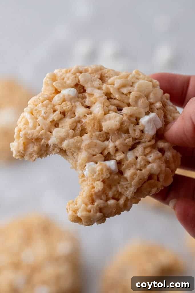 Crumbl-Style No-Bake Rice Krispies Treats 2 Crumbl rice krispies bar cookies with a bite taken out of them
