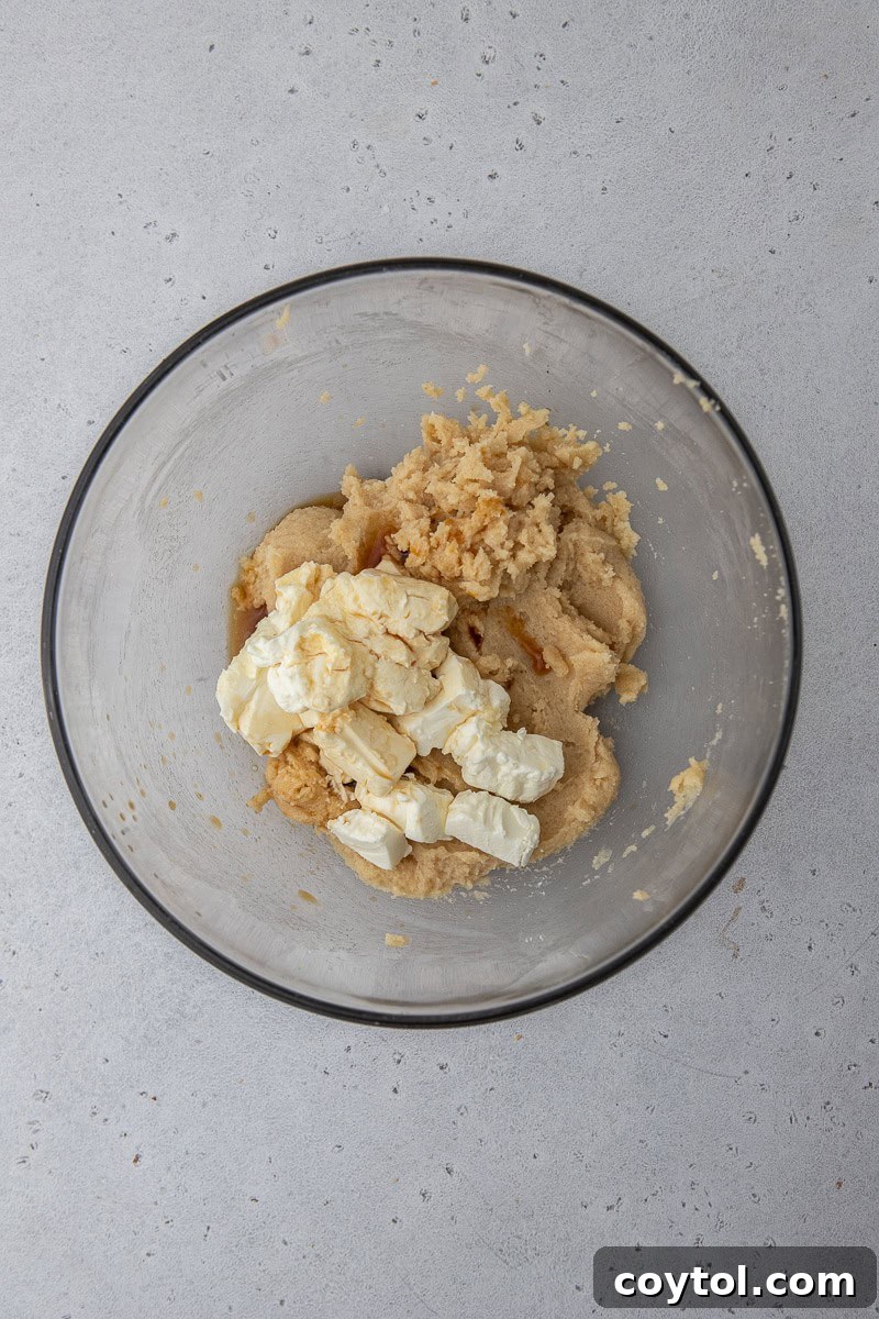 Wet ingredients (butter, sugars, cream cheese, vanilla) mixed together in a bowl, ready for dry ingredients.