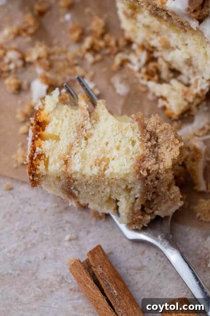 Fork holding coffee cake slice with crumble topping