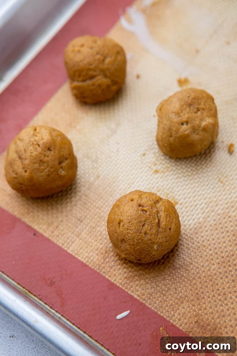 Rolled pumpkin balls chilling on a baking sheet lined with parchment paper