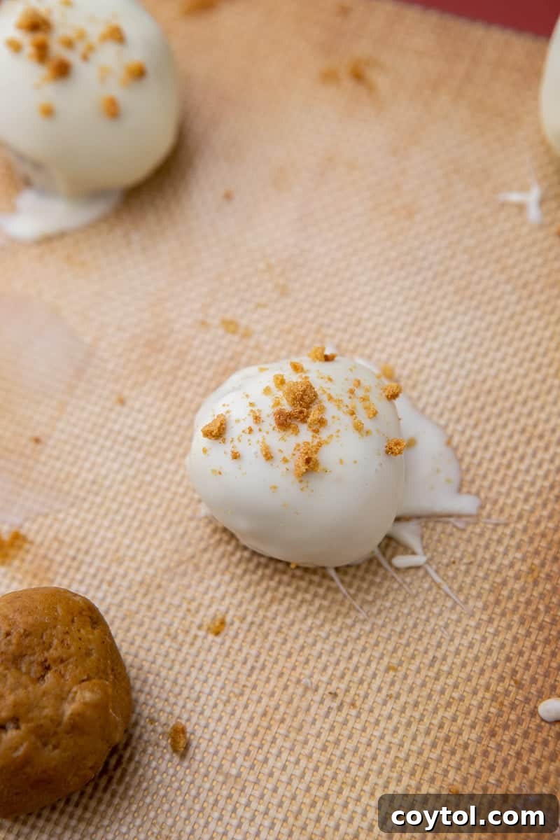 Pumpkin truffle being dipped into melted white chocolate