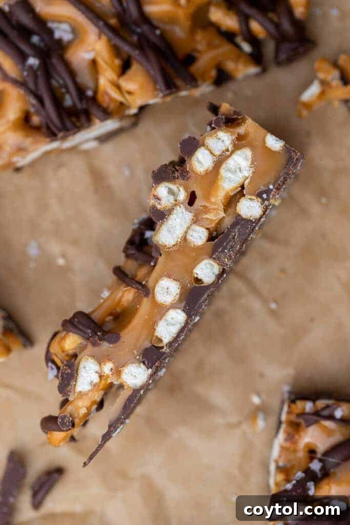 A piece of salted caramel pretzel bark with dark chocolate drizzle on its side