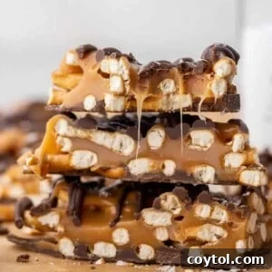 A stack of ooey gooey salted caramel pretzel bark pieces on parchment paper.