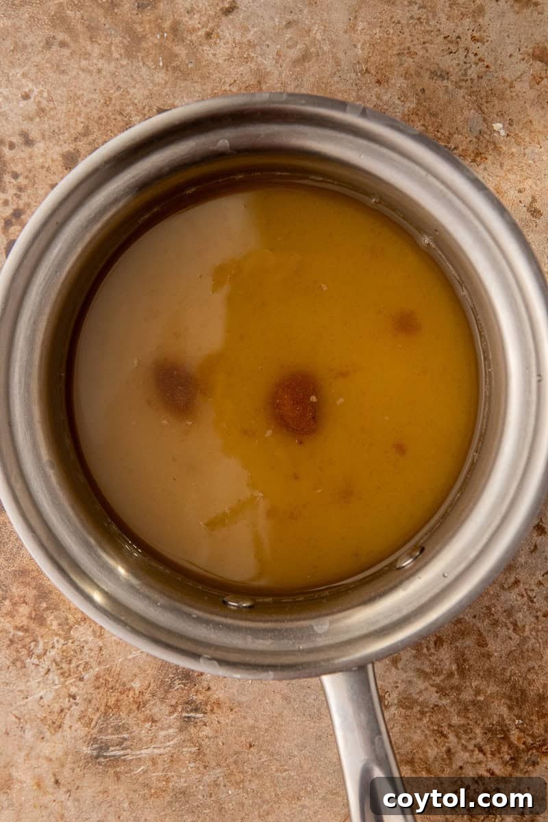 Simple syrup simmering in a saucepan on the stove, showing the initial stages of making the homemade sugar cookie syrup.