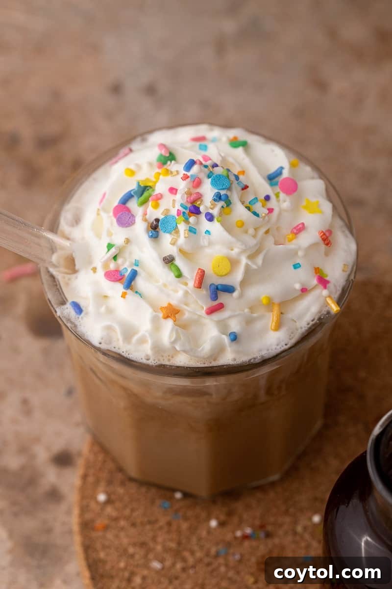 A beautifully prepared iced latte, made with homemade sugar cookie syrup, topped with whipped cream and sprinkles, ready to be enjoyed.