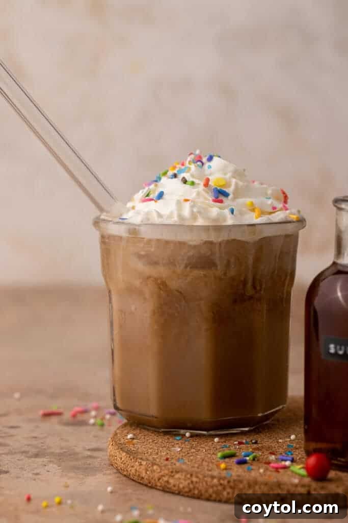 A refreshing cold brew sugar cookie drink, topped with cold foam, served in a clear cup with festive sprinkles, demonstrating its appeal in iced beverages.