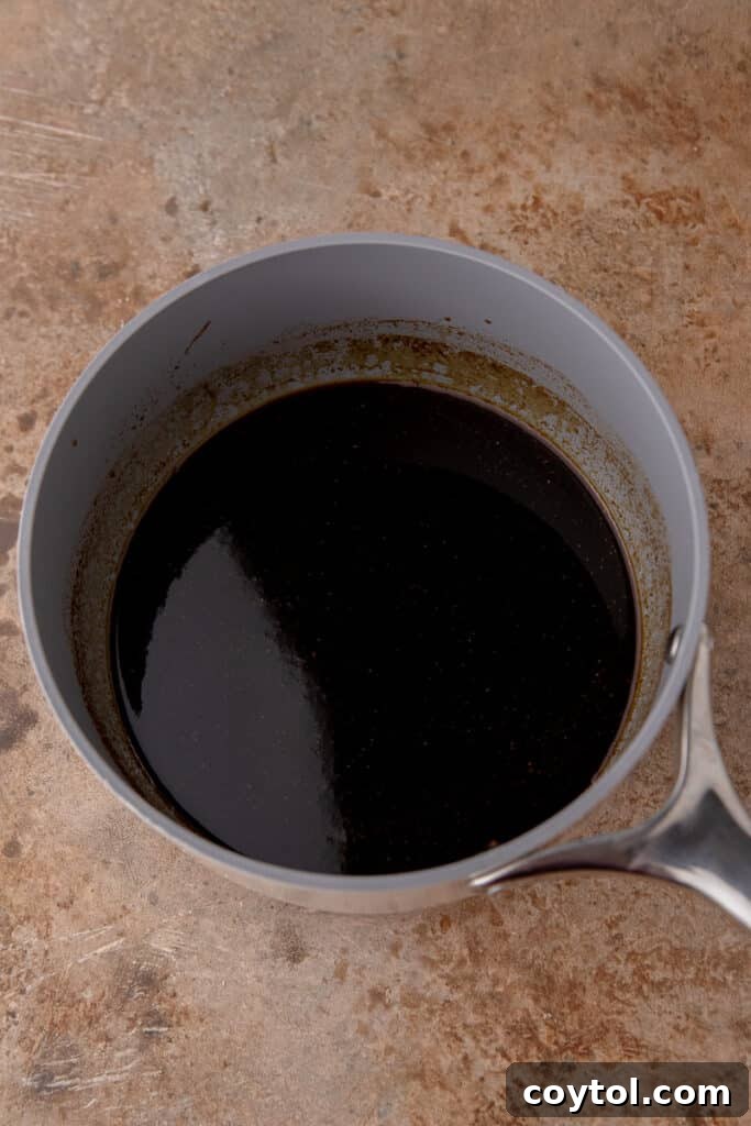 Dark, glossy syrup in a saucepan after simmering and thickening.
