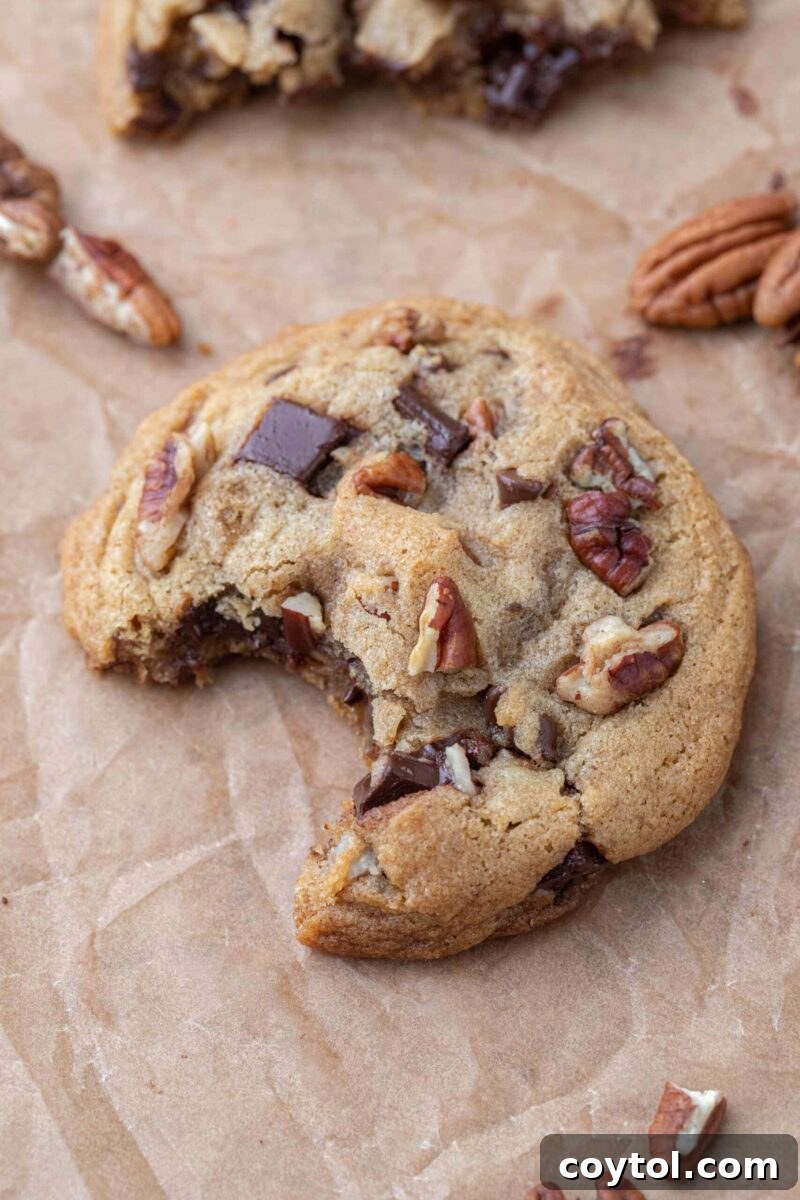 A beautiful stack of chewy brown butter pecan chocolate chip cookies, garnished with a sprinkle of flaky sea salt, ready to be enjoyed.