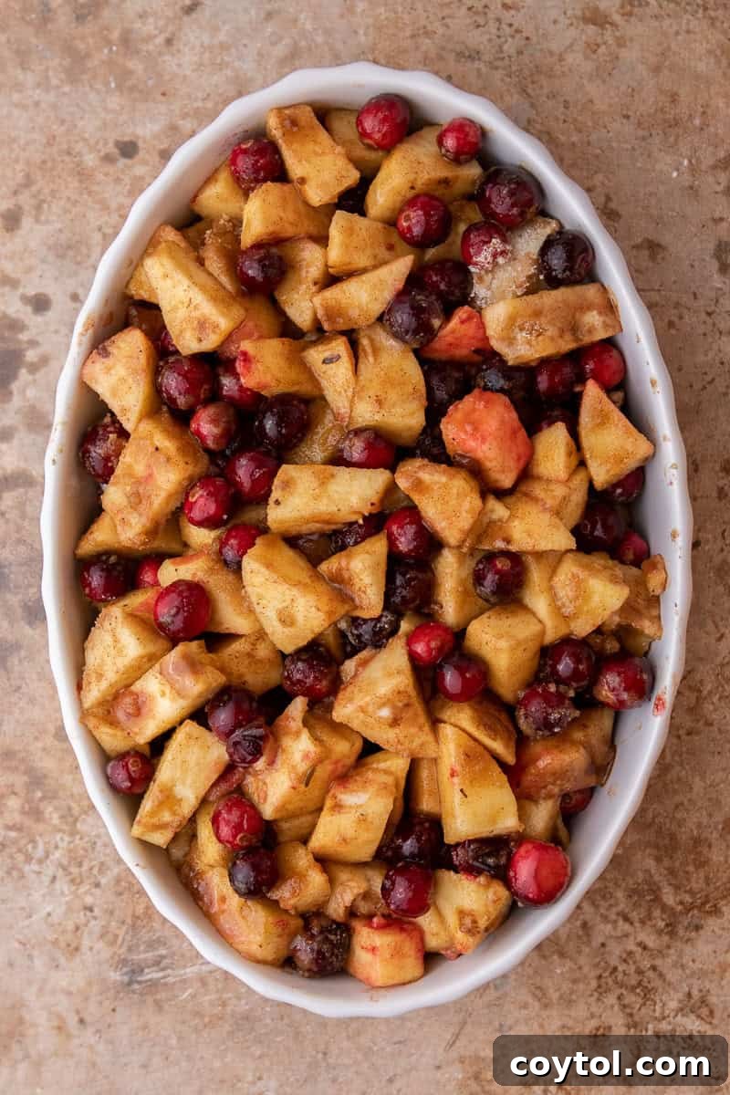 The cranberry and apple fruit filling spread evenly in a glass baking pan, ready for the topping.