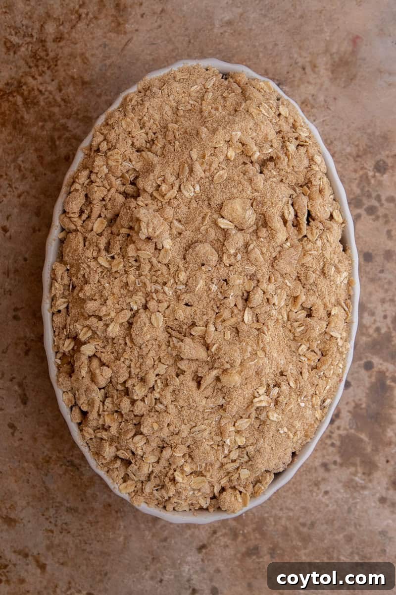 Unbaked cranberry apple crisp, generously topped with streusel, placed in a baking dish and ready for the oven.