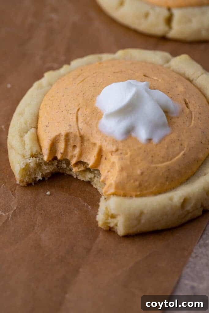 Crumbl's Divine Pumpkin Pie Cookies 2 Close up of a Crumbl pumpkin pie cookie with a bite taken out of it, showcasing the soft cookie base and creamy pumpkin filling.